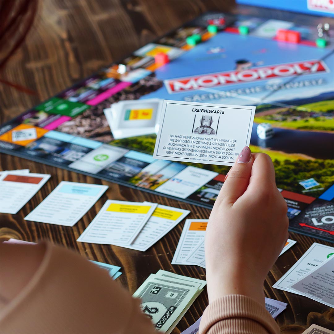 Monopoly Sächsische Schweiz - Spieler hält negative Ereigniskarte in der Hand