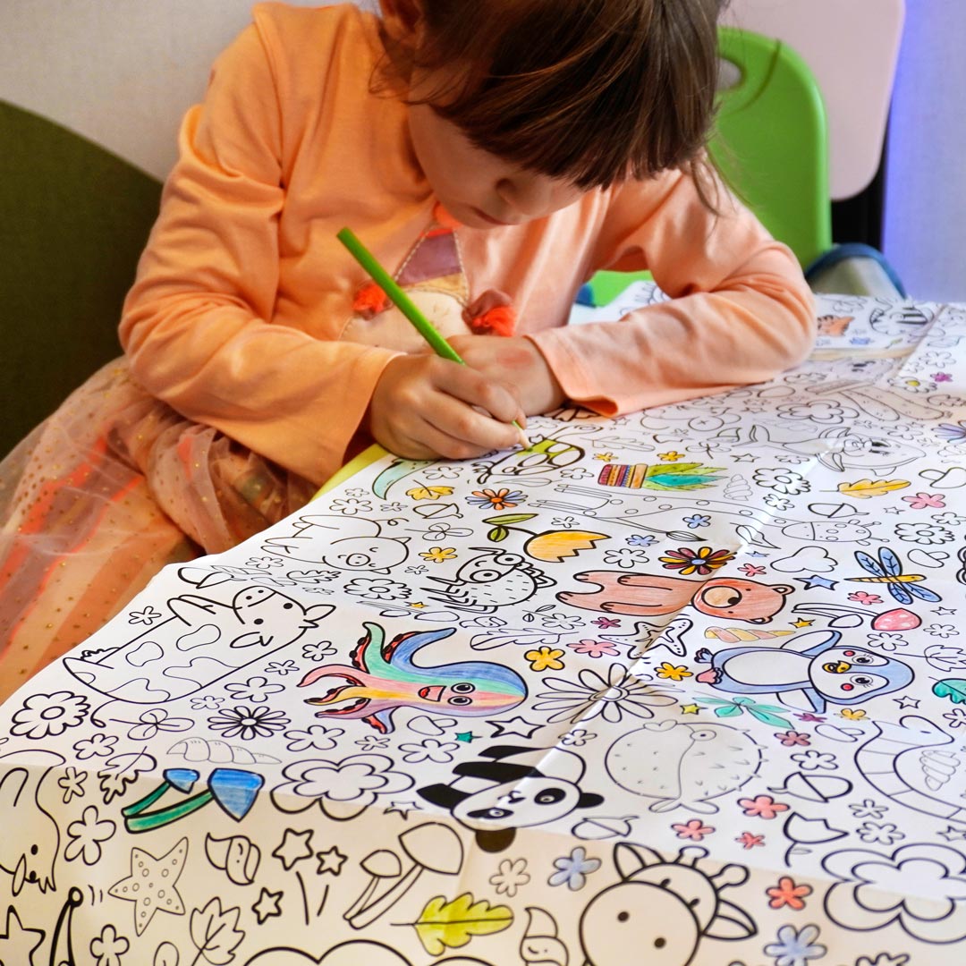 Mädchen malt begeistert die Motive der Ausmaltischdecke aus